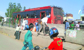 People wait for buses near the national highway at Lalru