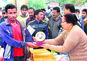 Sumit Kumar of Delhi being awarded a trophy for winning the Bhawali Open Marathon by local legislator Sarita Arya at Bhimtal on Sunday.