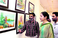 An artist shows his works to a visitor at an exhibition in Virsa Vihar, Jalandhar