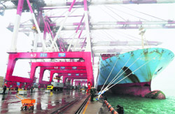 Employees unload containers from a cargo ship as frontier inspection soldiers (C) stand guard at Qingdao port in Shandong province during a rainy day. China posted a US $5.35 billion trade surplus in March as import growth eased back from a 13-month peak while exports grew faster than expected, customs data showed.