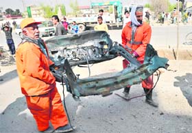 Municipality workers carry a part of car that bore the brunt of Sundays suicide attack in Kabul