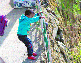 A child plays with a damaged railing in Lakkar Bazar in Shimla.
