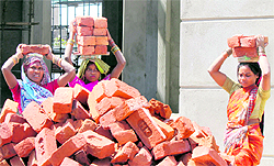 Women labourers carry bricks at a construction site in Jammu