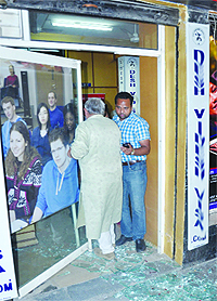 The broken glass of the door of travel agents office lies scattered on the floor near Narinder Cinema in Jalandhar on Wednesday