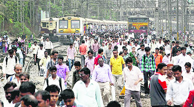 Office-goers walk on the tracks as chaos prevails at a Mumbai railway station during rush hour on Wednesday.