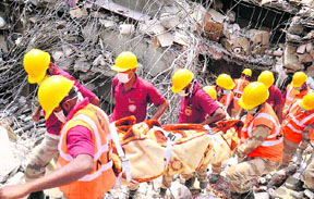 Members of a rescue team bring out a body from the debris of Shital Fibres building that collapsed on Sunday night