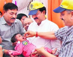 Haryana Health Minister Rao Narender Singh administers anti-polio drops to a child held by Gurgaon Civil Surgeon Dr Praveen Garg, while Sports Minister Sukhbir Kataria looks on during a recent round of pulse-polio drive in Gurgaon
