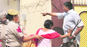A woman tries to resist the demolition of a portion of the boundary wall of her house.