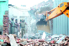 Cops prevent a man from moving ahead as demolition takes place. 