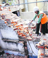 A worker removes illegal encroachments during the Chandigarh Housing Board demolition drive in Sector 29, Chandigarh, on Friday.