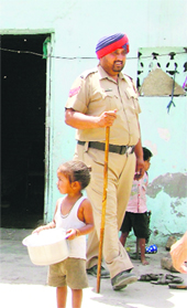 A file photo of a child carrying a utensil to help his parents move household articles following a demolition drive carried out in Ludhiana on Thursday.