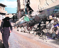 A woman walks past the rubble of homes destroyed during army shelling in Taftnaz, in northwestern Syria.