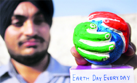 Amritpal Singh shows his creation, a model of Earth held between two hands, on the eve of World Earth Day in Amritsar on Saturday.