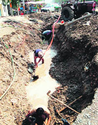 Employees of the Municipal Corporation repair the broken water supply pipeline on Majitha Road in Amritsar on Monday.