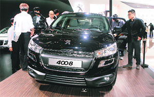Visitors look at the Peugeot 4008 at the Auto China 2012 in Beijing on Tuesday. PSA Peugeot Citroen said it may build cars in India with General Motors, its new global alliance partner, effectively scrapping a planned 650 million euro ($859 million) investment in its own factory