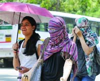 IN THE FACE OF HEAT WAVE: Girls cover themselves while walking on the road in New Delhi on Wednesday
