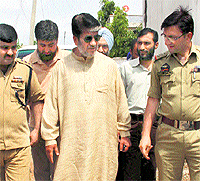 Policemen accompany Shabir Shah after he was put under house arrest
