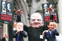 A man wearing a mask of Rupert Murdoch holds string puppets depicting British PM David Cameron (L) and Culture Secretary Jeremy Hunt in London.