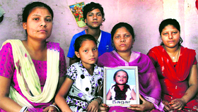 Sonia, mother of five-year-old Sagar, who died after falling into an open manhole, holds his picture as her children sit along in Jalandhar on Saturday.