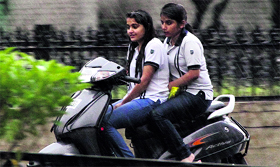 Caught unawares Girls ride a scooter during rain in Jalandhar on Saturday.