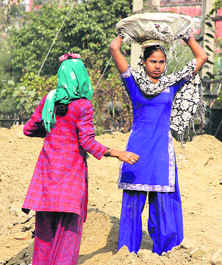 Two women labourers work at a construction site in Jalandhar on Monday.