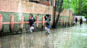 Girls run for cover during showers in Srinagar on Monday.