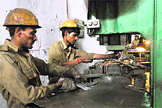 Migrant labourers in a factory and (right) two women labourers work at a construction site in Jalandhar on Monday.