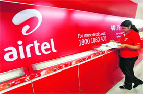 An employee checks a customers' feedback book next to a Bharti Airtel logo inside its shop in Kolkata. India's biggest mobile phone carrier by subscribers reported its ninth straight quarterly profit decline on Wednesday, hurt by intense price competition, higher interest costs and foreign exchange fluctuation losses