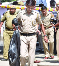 Delhi police officials carry the gun of Haryana police constable Surender who shot himself at Haryana Bhawan in New Delhi on Wednesday.