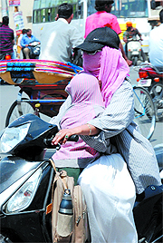 A mother covers herself and her child as protection against the summer heat near the Hanuman Chowk in Bathinda on Thursday.