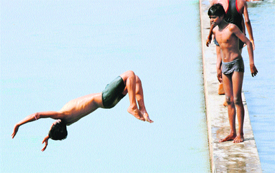 A boy jumps into a canal as another one looks on in Karnal.