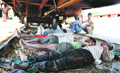 Unaware of the risk involved, labourers take a nap under a goods train during a hot afternoon at the railway station in Karnal.