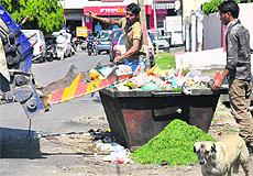 Sanitary workers remove garbage from a bin in Jammu.