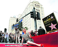 Actress Scarlett Johansson waves as she poses on her star after it was unveiled on the Walk of Fame in Hollywood, California