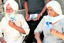 Mohinder Singh and Nirmal Kaur show pictures of their grandson Jatinder Singh in Kapurthala on Friday