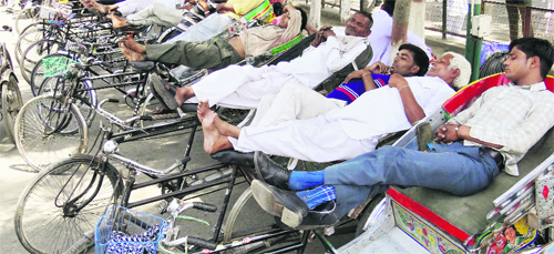Rickshaw pullers rest during a hot afternoon at Karnal railway station. 