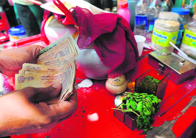 A shopkeeper counts rupee notes at a roadside food stall in Mumbai. The Indian currency fell to near a six-month low against the US dollar on Monday before recovering slightly, thanks to suspected central bank intervention, currency dealers said. The unit fell to an intraday low of Rs 53.74 to the greenback a level last seen in December, 2011  but then edged back up to 53.30 after the intervention.