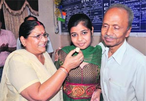 Parents of Pallavi Anand offer sweets to her on securing first position in Class XII examination of the Jammu and Kashmir State Board of School Education, in Jammu on Monday. 