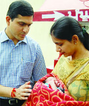 Deputy Commissioner Rajat Agarwal and his wife Ritu Agarwal hold a baby left in Panghura at Red Cross Bhavan in Amritsar on July 2011. 