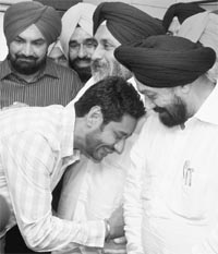 Singer Harbhajan Mann greets Punjab Deputy Chief Minister Sukhbir Singh Badal after taking over as the chairman of the Mohali Planning Board on Wednesday. 