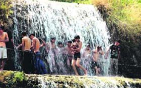 People have a bath under a waterfall in Sahastradhara in Dehradun on Wednesday