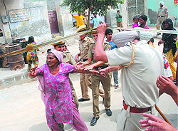 Police personnel hold back one of the residents of the area. The residents were protesting against the dumping of city's sewage in their neighbourhood