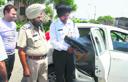 A traffic policeman removes black film from the window of a car in Ludhiana on Thursday.