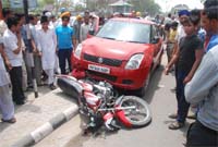 Onlookers crowd around the Maruti Swift car and the bike involved in the accident in which a junior engineer was seriously injured. The accident took place at the Liberty Chowk in Bathinda on Friday. 