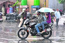 A couple rides a motorcycle as downpour lashes Jammu on Saturday.
