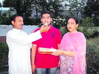 Parents of Varun offer sweets to him. 
