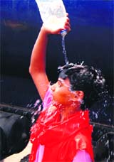 A child uses water from a tanker sent by a welfare society to cool off in Amritsar on Sunday.