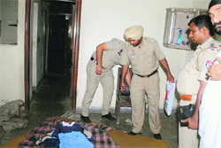 Policemen inspect the spot where a 60-year-old security guard was found murdered in Ludhiana on Sunday. 