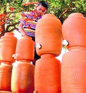 A boy checks his earthen pots fitted with taps, which have replaced traditional pitchers, in Chandigarh on Tuesday