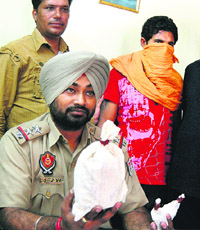 A police official shows the heroin seized from Satnam Singh (with covered face) in Jalandhar.